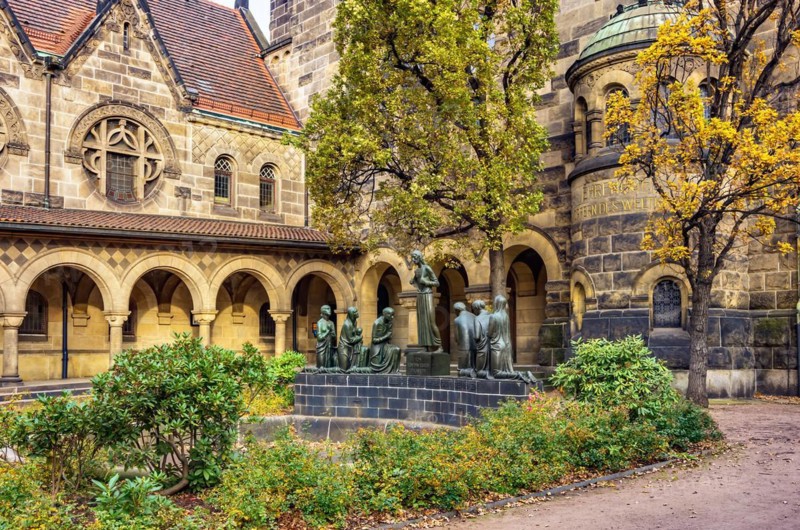 Court of honour with arcades and group sculpture of the Consoling Christ by Selmar Werner. The church