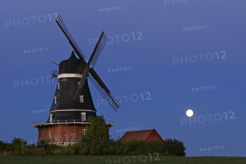 Traditional windmill in field at full moon