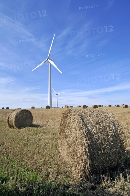 Wind turbines in mowed field with hay bales