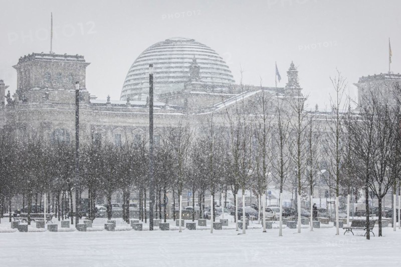 The Reichstag building is silhouetted against snowfall in the government district in Berlin