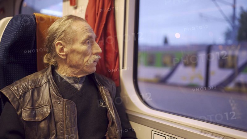 Close up of senior with glasses travels in a train and looks at out the window