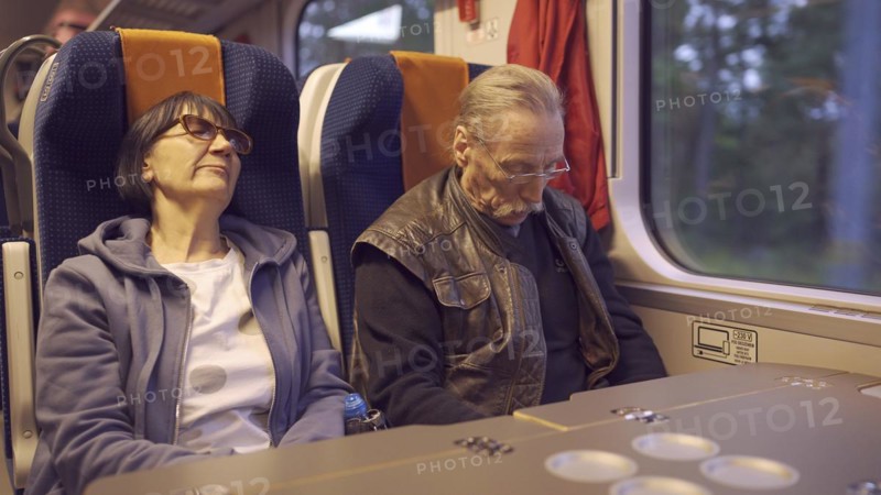 An elderly couple ride the train early in the morning and sleep