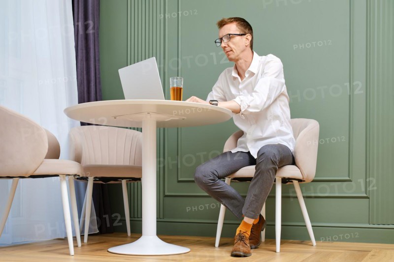 Middle aged man using laptop at home sitting in living room
