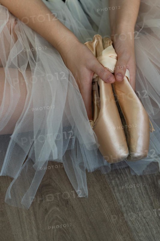 Legs of girl dancing ballet with tulle skirt and pink shoes different dance steps wooden floor and white background with copy space