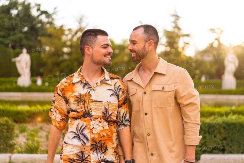 Romantic portrait of gay newlyweds walking in the sunset in a park in the city