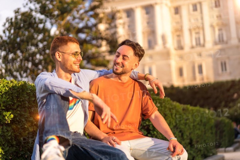 Portrait of gay newlyweds sitting in the park at sunset in a park in the city