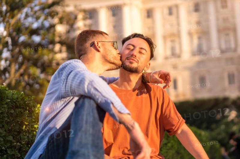 Portrait of gay newlyweds sitting in the park at sunset in a park in the city