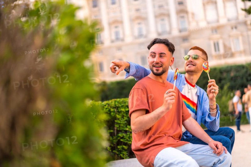 Smiling wedding couple eating a lollipop in the park on sunset in the city