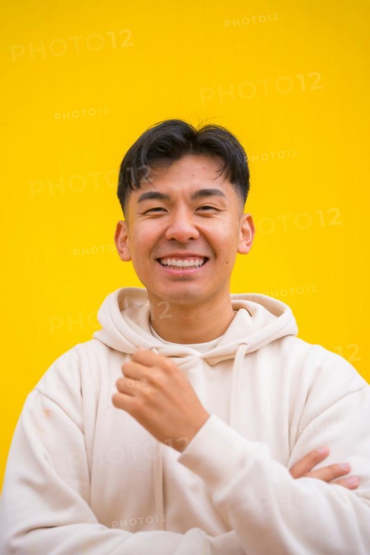 Portrait of a handsome South Korean Asian man in basic clothes smiling isolated over yellow background