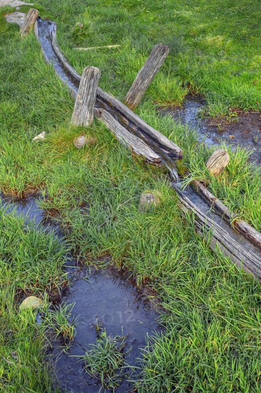 Wooden water pipe in green meadow