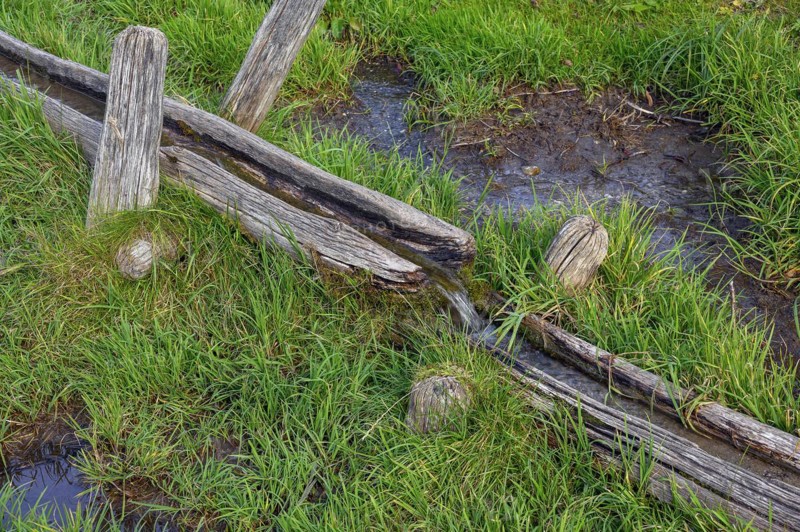 Wooden water pipe in green meadow
