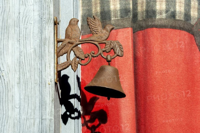Two birds with a bell on a door