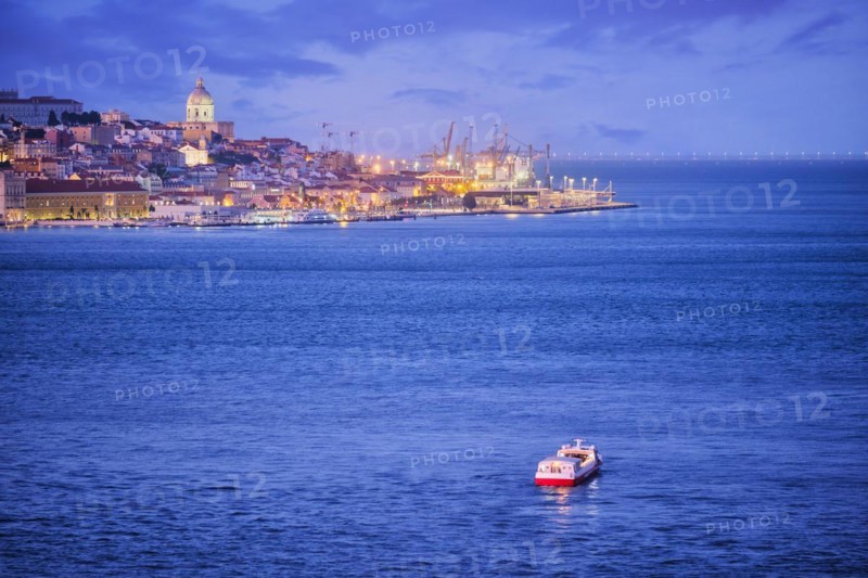 Night view of Lisbon over Tagus river from Almada with ferry and tourist boat in evening twilight