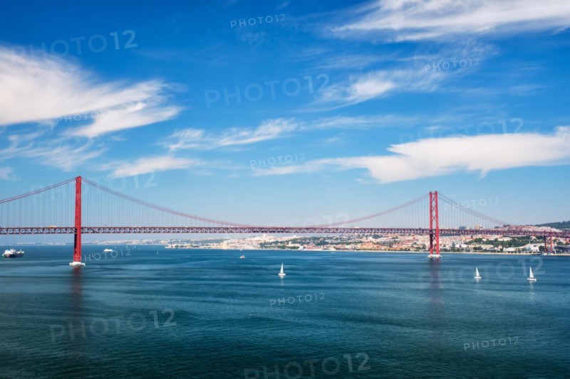 View of 25 de Abril Bridge famous tourist landmark of Lisbon connecting Lisboa to Almada on Setubal Peninsula over Tagus river with boats yachts and vessels