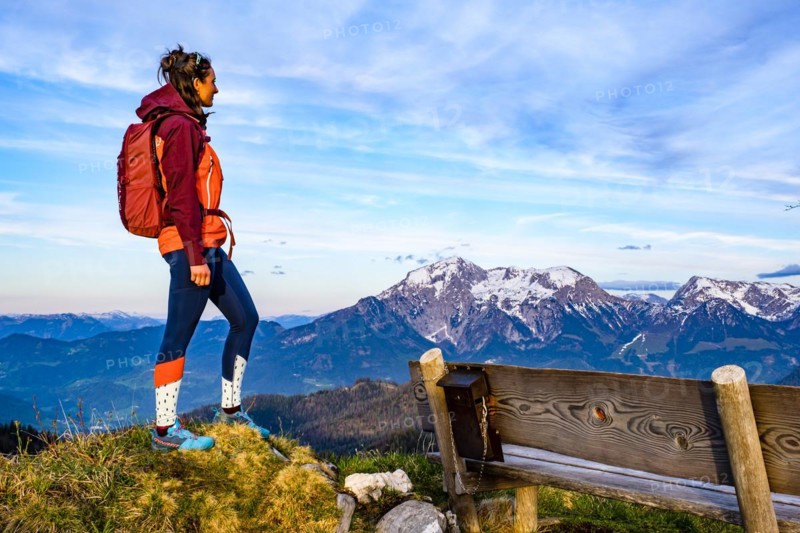 Mountaineer next to a wooden bench enjoying the view towards Hoher Göll