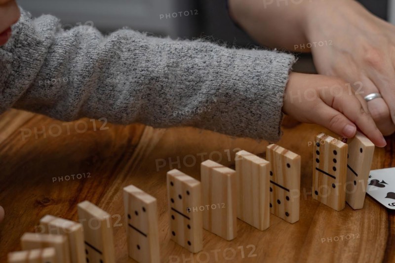 Child's hands in gray sweater playing dominoes with blurred focus