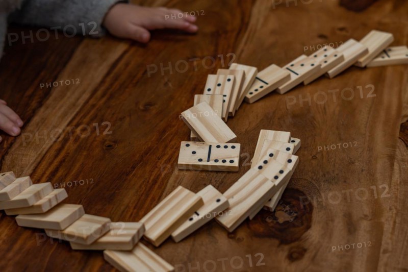 Child's hands in gray sweater playing dominoes with blurred focus