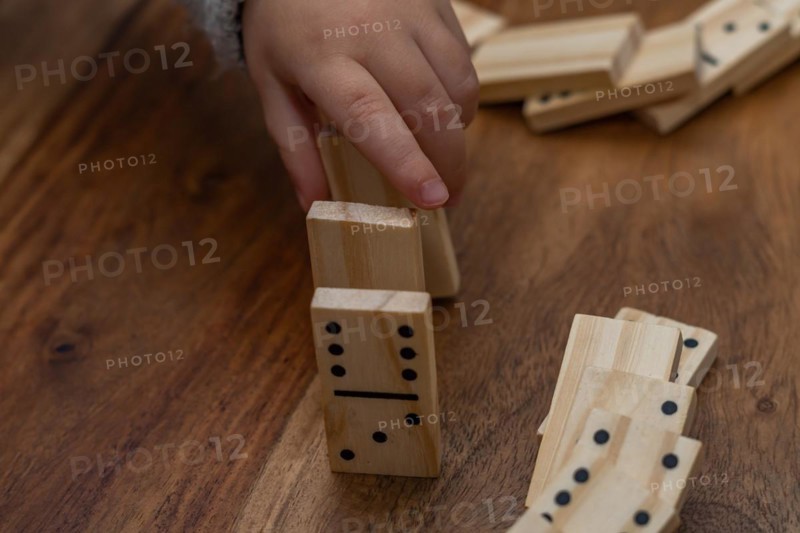 Child's hands in gray sweater playing dominoes with blurred focus