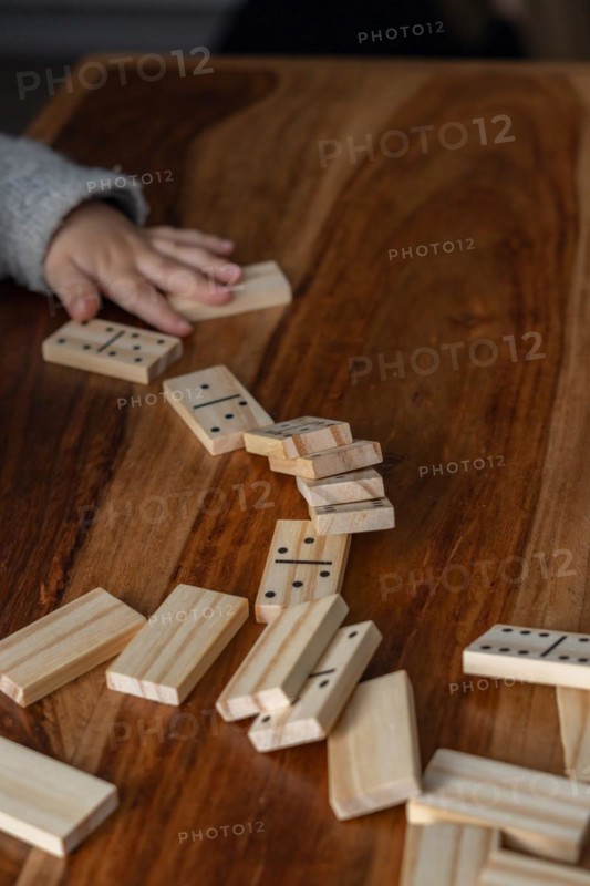 Child's hands in gray sweater playing dominoes with blurred focus