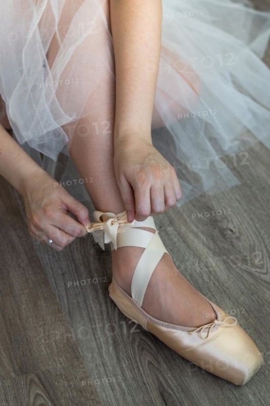 Legs of girl dancing ballet with tulle skirt and pink shoes different dance steps wooden floor and white background with copy space