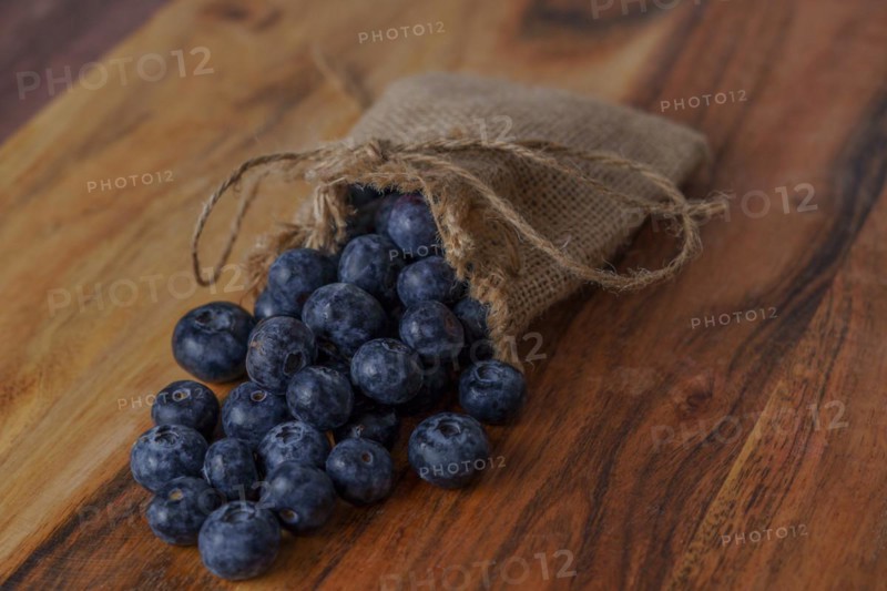 Fresh blueberries in a raffia bag on a wooden table
