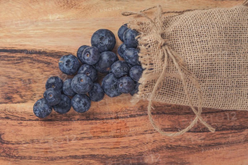 Fresh blueberries in a raffia bag on a wooden table
