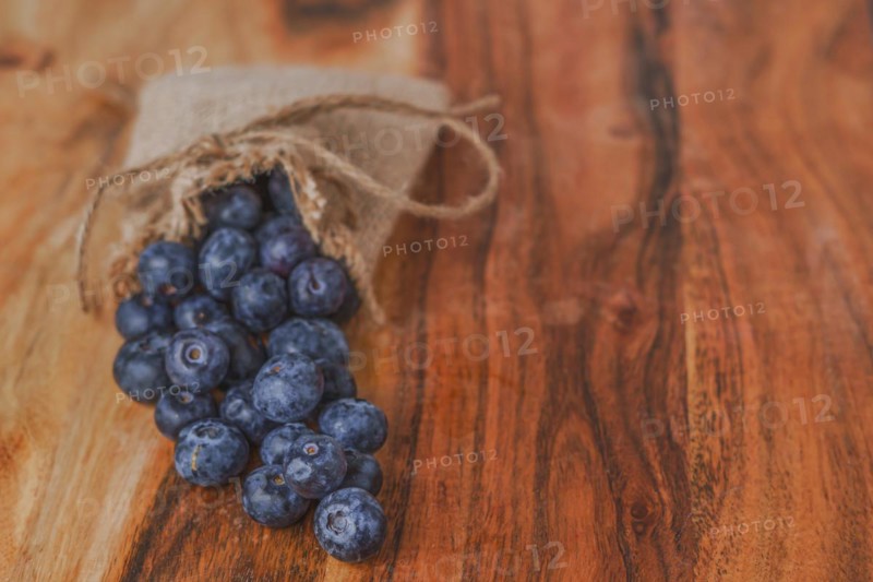 Fresh blueberries in a raffia bag on a wooden table