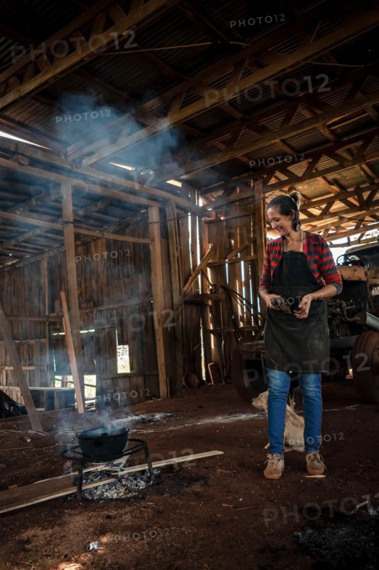 The young woman in uniform working in a factory cooking for the all with fire on the floor