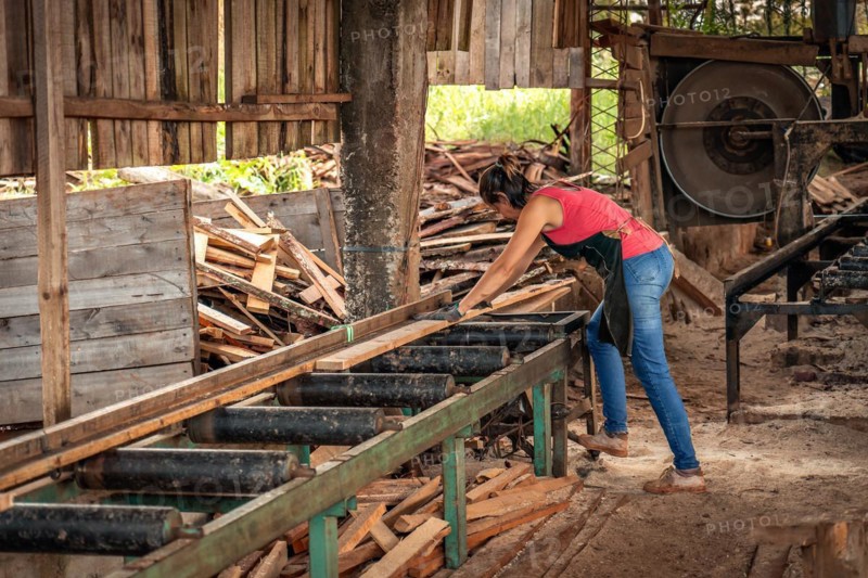 Portrait of middle-aged woman in apron working with a machine in a sawmill