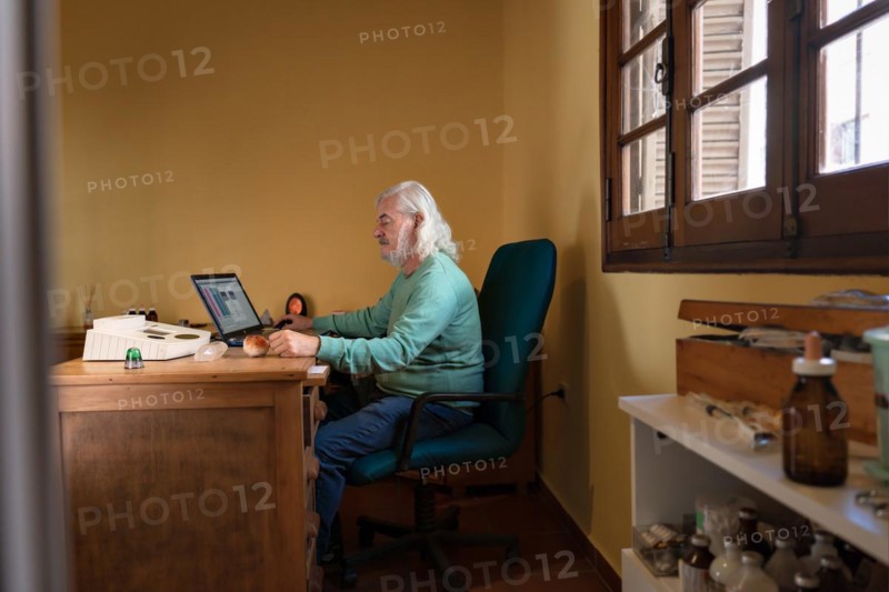 General shot of an elderly man sitting at his desk performing a quantum medicine analysis