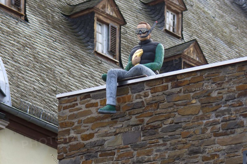 Male figure with diving goggles and snorkel sitting on a wall