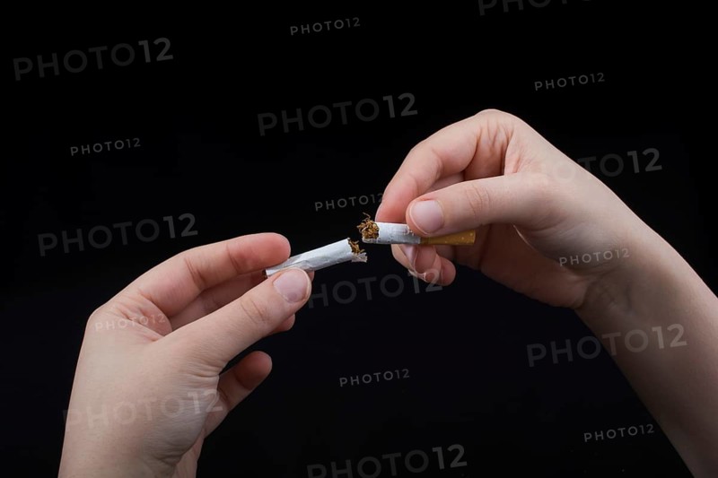 Hand is breaking a cigarette on a black background