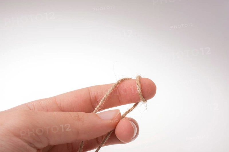 Hand holding linen thread on a white background