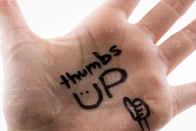 Thumbs up written on hand palm on a white background