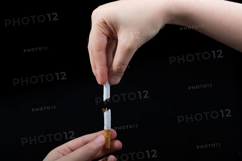Hand is breaking a cigarette on a black background