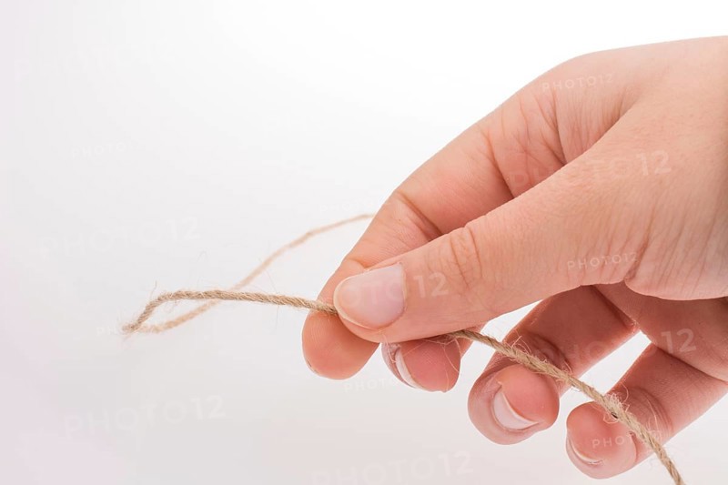 Hand holding linen thread on a white background