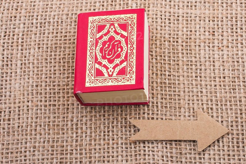 Paper arrow and Islamic Holy Book Quran in mini size