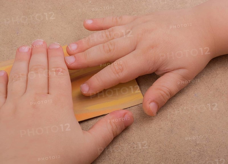 Hand holding painted note paper on brown background