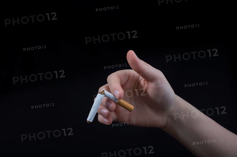 Hand is breaking a cigarette on a black background