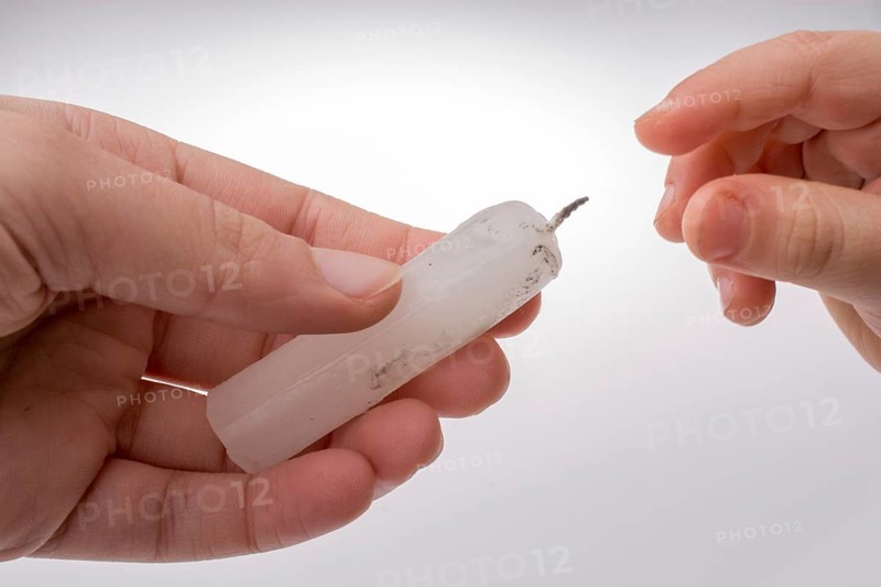 White candle stick in hand on a white background