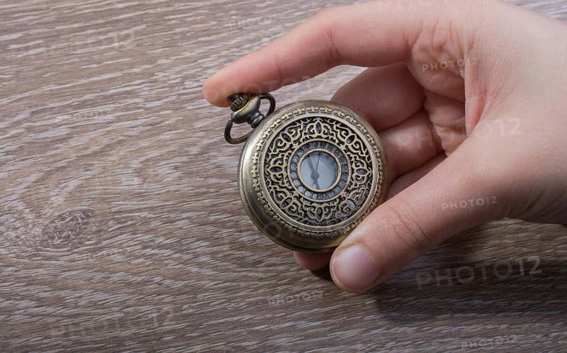 Retro style pocket watch in hand on black background
