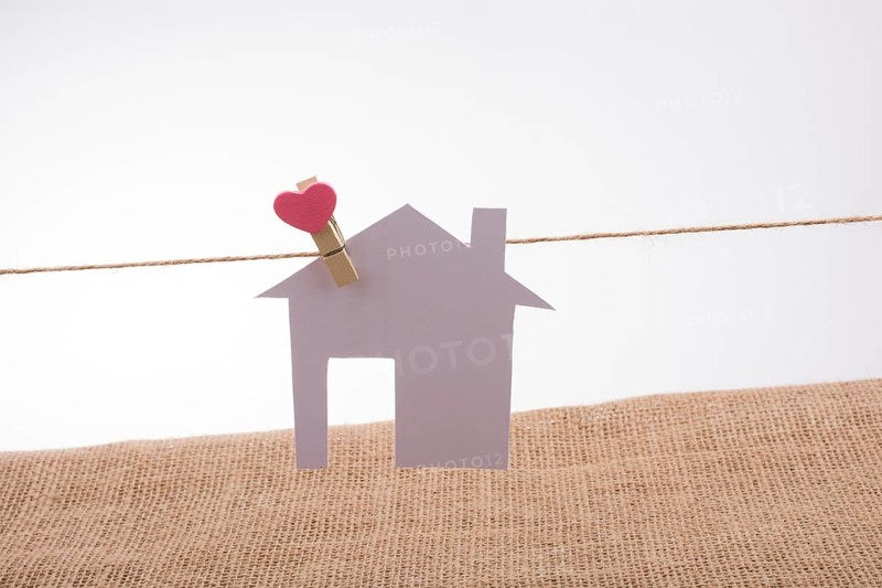 Little paper house attached to a string with a heart clip