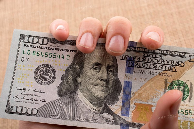 Hand holding banknote bundle of US dollar on a linen canvas background