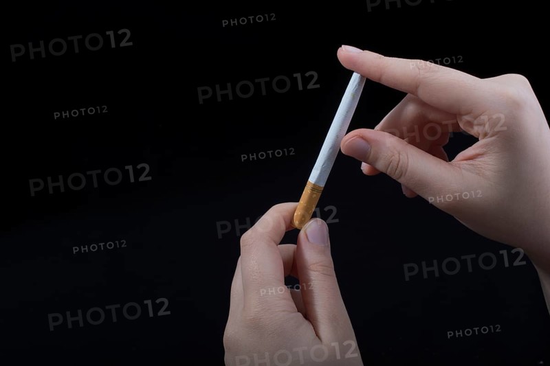Hand is breaking a cigarette on a black background