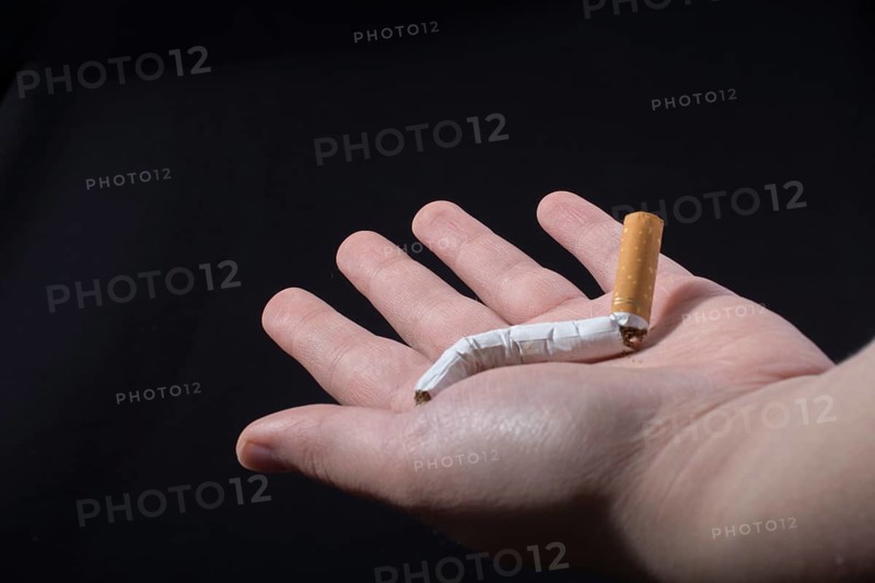 Hand is breaking a cigarette on a black background