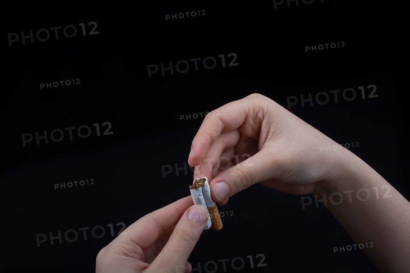 Hand is breaking a cigarette on a black background