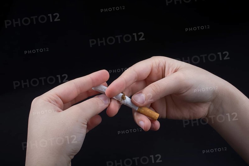 Hand is breaking a cigarette on a black background