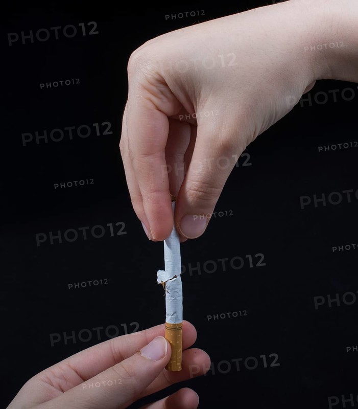 Hand is breaking a cigarette on a black background