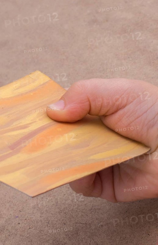 Hand holding painted note paper on brown background