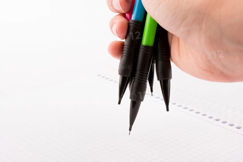 Mechanical pencils of various color in hand on white background
